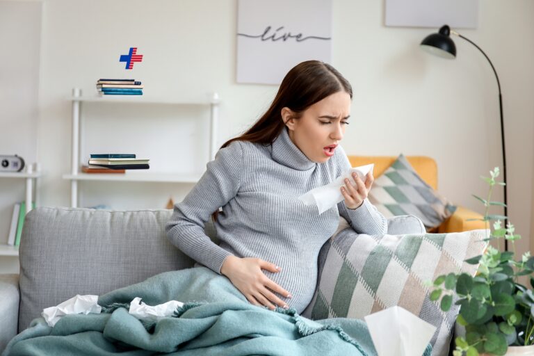 Coughing pregnant woman at home to illustrate whooping cough. / Várandós nő köhög otthon a lakásban, szamárköhögés illusztráció.